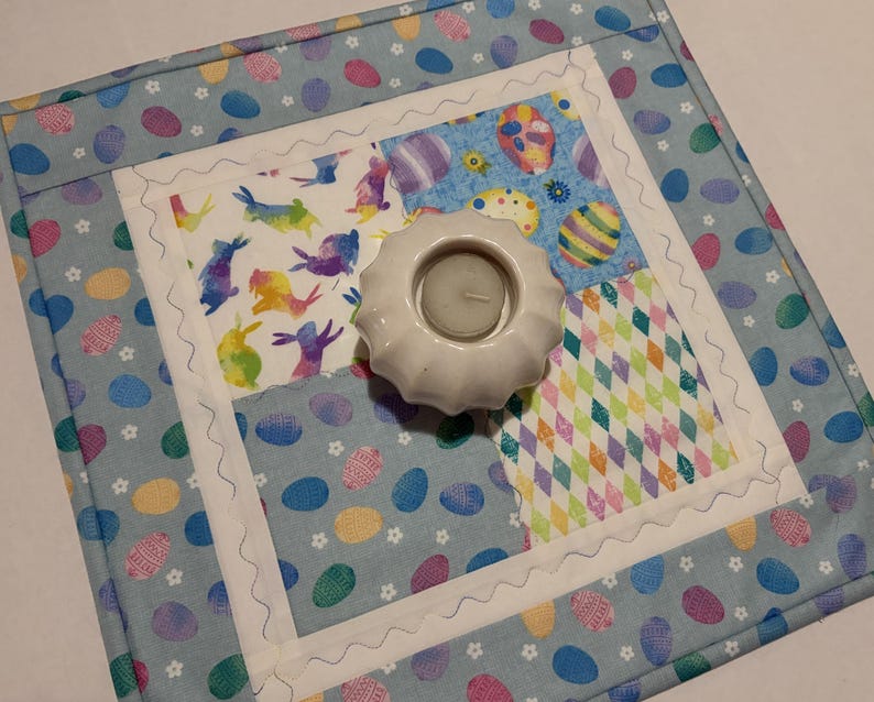 K&ouml;nnte beinhalten: Eine wei&szlig;e Keramik-Tasse mit schwarzem Henkel und dem Text "But First, Coffee" in fetter, schwarzer Schrift. Die Tasse steht vor einem verschwommenen Hintergrund, der eine gem&uuml;tliche Umgebung suggeriert.