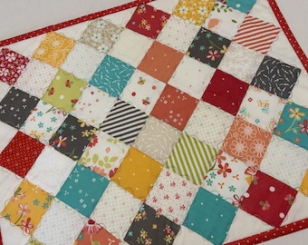 May include: A patchwork quilt featuring a grid of square fabric patches in various colors including red, yellow, teal, and gray, with diverse floral, striped, and polka dot patterns. The quilt is finished with a red and white polka dot border.