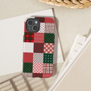 Op de afbeelding: Een rechthoekig smartphonehoesje met een patchworkontwerp van diverse rode, groene en witte patronen, waaronder ruiten, strepen, stippen en geometrische vormen. Het hoesje heeft een zwarte uitsparing voor de camera aan de achterzijde.