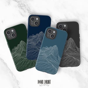 Puede incluir: Cuatro fundas para teléfono en tonos verde, azul y negro, cada una con un diseño de montaña en línea blanca. Las fundas están dispuestas sobre una superficie de mármol. El texto "DOMI PRINT studio" está en la parte inferior.