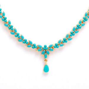May include: A gold-toned necklace featuring turquoise-colored stones. The necklace has a floral design with a central pendant. The turquoise stones are arranged in a leaf-like pattern, creating an elegant and eye-catching piece of jewelry.