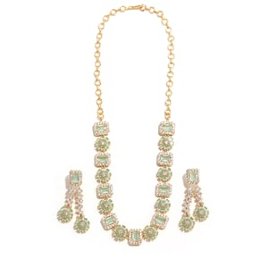 May include: A gold-toned necklace and matching earrings set. The necklace features rectangular light green stones surrounded by clear crystals. The earrings have a similar design, with dangling elements. The jewelry is set against a white background.