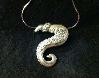 May include: A silver seahorse pendant necklace with a detailed design and a textured surface. The seahorse is adorned with small, round, white stones.