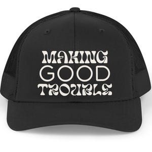 May include: A white ceramic mug with a black handle and the text "But First, Coffee" in a black, handwritten-style font. The mug is on a white surface.