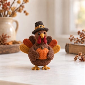 May include: A needle-felted turkey figurine made of brown wool, wearing a dark brown pilgrim hat with a yellow buckle. The turkey has red wattles, a yellow beak, and holds a small orange pumpkin. Its tail feathers are orange, yellow, and brown.