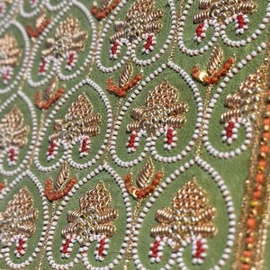 Close-up of gold zari, pearl beads and red thread hand embroidery on green silk, a premium handmade gift for girlfriend, boyfriend, husband or wife.