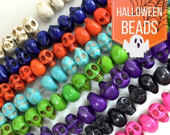 May include: A strand of colorful skull beads, featuring various colors like turquoise, green, purple, black, and pink. The beads are made of a smooth, polished stone and have a detailed skull design.  Halloween Beads.