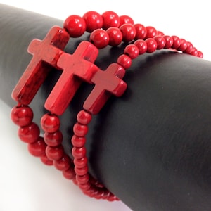 May include: Red beaded bracelet with three red wooden cross charms.
