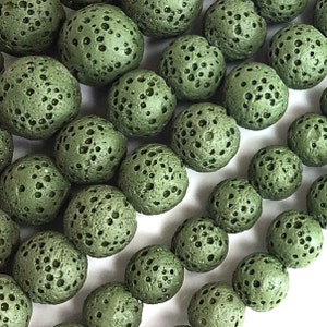 May include: A close-up of a collection of green lava rock beads. The beads are round and have a porous texture. They are perfect for making jewelry or other crafts.