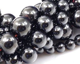 May include: A strand of black hematite beads, each bead is round and smooth with a high polish. The beads are strung on a thin black cord.