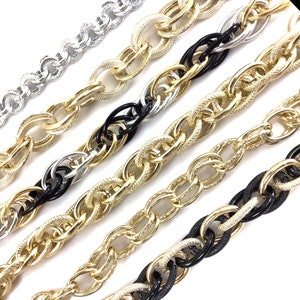 May include: Five different chain styles in gold, silver, and black. The chains are all linked together and are laying on a white surface.