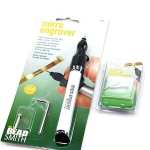 May include: A white and black micro engraver tool with a green and white packaging. The packaging includes the text "micro engraver" and "PRO QUALITY".