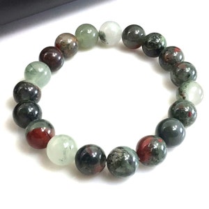 May include: A bracelet made of round, multi-colored gemstone beads. The beads are a mix of green, black, and red.