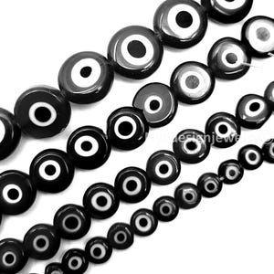 May include: Strands of black and white evil eye beads in various sizes. The beads have a glossy finish and a circular design with a white iris, a black pupil, and a white and black outer ring. The beads are strung together.
