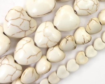May include: A strand of white heart-shaped beads with brown marbling. The beads are arranged in rows of decreasing size.