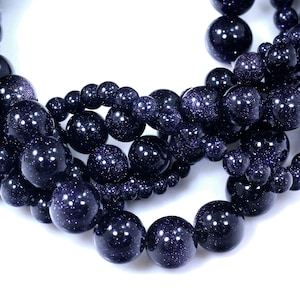 May include: A strand of dark blue gemstone beads with a sparkly, speckled texture. The beads are round and uniform in size.