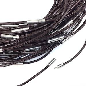 May include: A bundle of brown leather cords with silver magnetic clasps. The cords are approximately 18 inches long and are perfect for making necklaces, bracelets, or other jewelry.