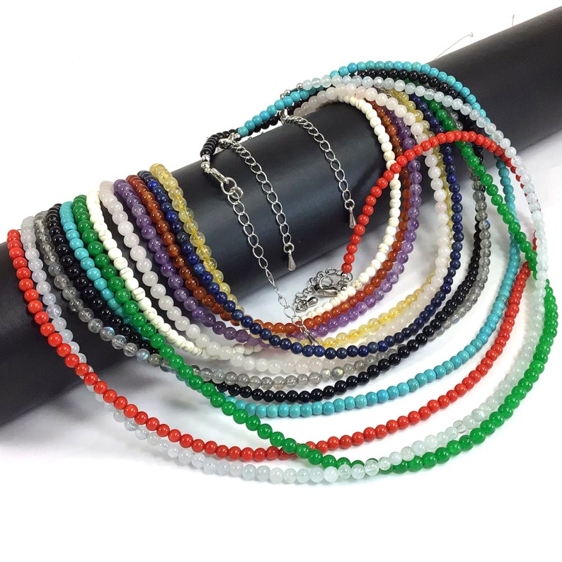 May include: A collection of 18 different colored gemstone bead necklaces. The necklaces are made of various stones, including turquoise, red coral, and amethyst. Each necklace is approximately 18 inches long.