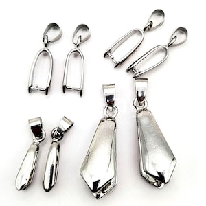 May include: A collection of silver-colored pendant bails and pendant settings. The bails have a loop at the top and a U-shaped base. The pendant settings are in various shapes, including teardrop and geometric designs. These jewelry findings are displayed on a white background.