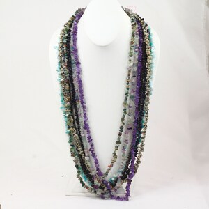 May include: Multi-strand necklace made of various semi-precious stones, including amethyst, turquoise, and black onyx. The necklace is layered and features a variety of shapes and sizes of stones.