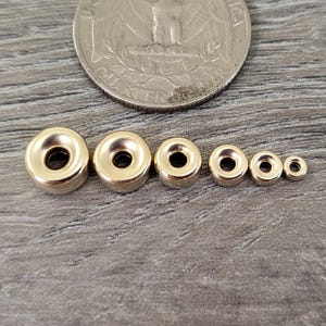 Pu&ograve; includere: Sei perline magnetiche in metallo color oro di diverse dimensioni. Le perline sono disposte in ordine di grandezza, con la perlina pi&ugrave; grande a sinistra e la pi&ugrave; piccola a destra.