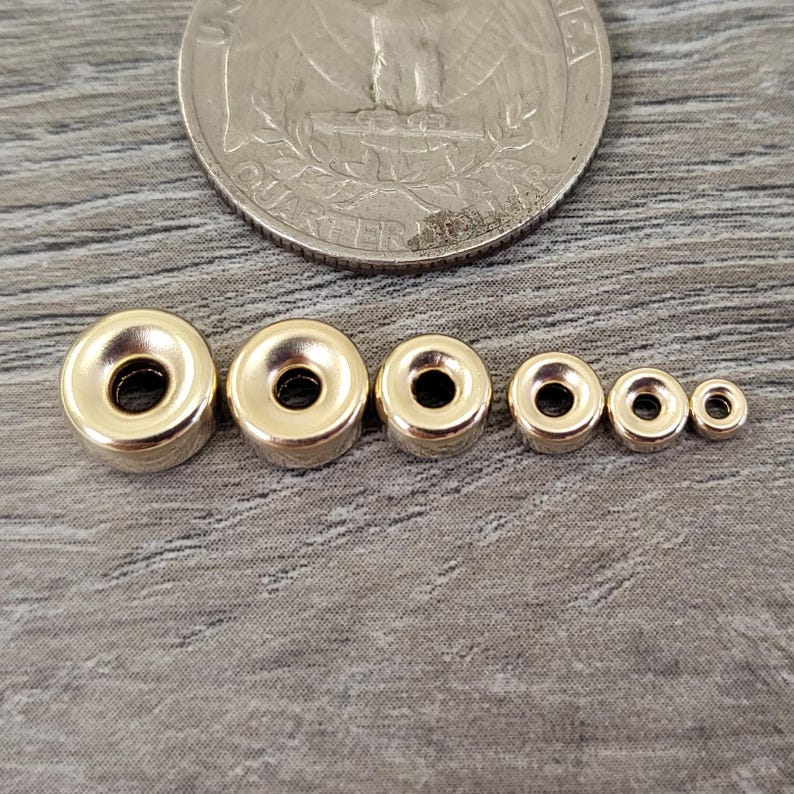 Pu&ograve; includere: Sei perline magnetiche in metallo color oro di diverse dimensioni. Le perline sono disposte in ordine di grandezza, con la perlina pi&ugrave; grande a sinistra e la pi&ugrave; piccola a destra.