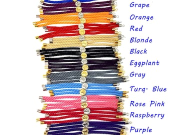 May include: A collection of 15 colorful rope bracelets with gold accents. The bracelets are arranged vertically, with the colors ranging from navy blue to brown. Each bracelet has a small gold charm attached to it.