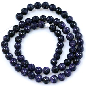 May include: A strand of dark blue gemstone beads with a speckled, glittery finish. The beads are round and uniform in size.