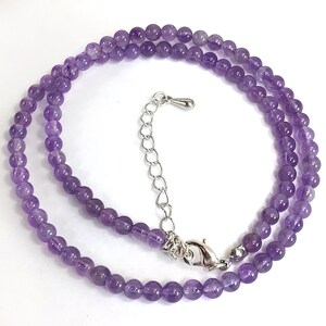 May include: A delicate amethyst gemstone necklace with a silver clasp and extender chain. The necklace is made of small, round beads and is perfect for layering.