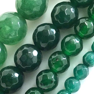 May include: A strand of green gemstone beads with a faceted finish. The beads are round and have a smooth, polished surface.