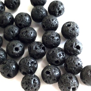May include: A close-up of a pile of black lava rock beads. The beads are round and have a rough, textured surface.