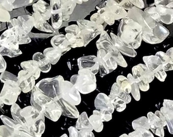 May include: A strand of clear quartz chip beads. The chips are irregular in shape and size, and they have a translucent, glassy appearance.