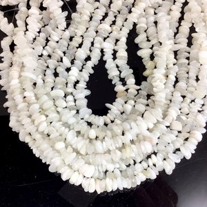 May include: A strand of white moonstone chip beads. The beads are smooth and polished, and they have a slightly iridescent sheen.