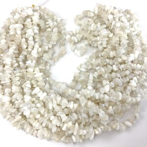 May include: A strand of white moonstone chip beads. The beads are irregular in shape and have a slightly iridescent sheen.