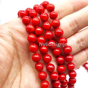 May include: Close-up of a strand of bright red, round beads. The beads are strung together on a red cord. The image includes the text "Ny6designjewelry &copy;".