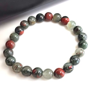 May include: A bracelet made of round, green, red, and black gemstone beads.