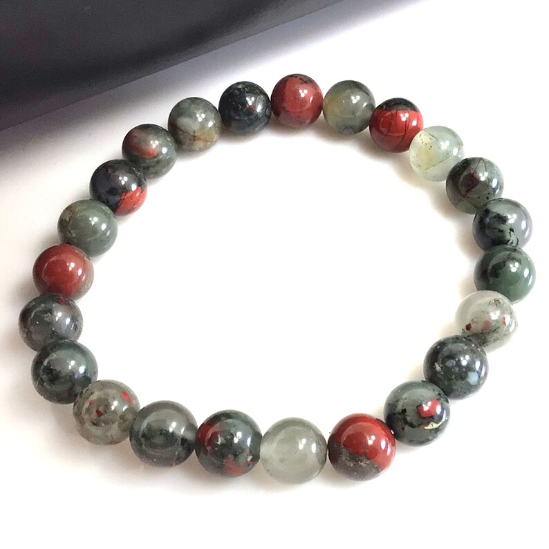 May include: A bracelet made of round, green, red, and black gemstone beads.