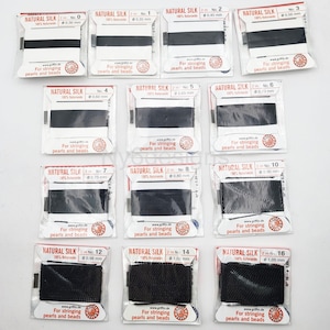 May include: A set of 10 spools of black natural silk thread for stringing pearls and beads. Each spool is labeled with the thread size in millimeters and the number of meters of thread on the spool.