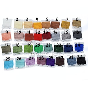 May include: Thirty-two spools of thread in various colors, numbered 1 through 32. The spools are arranged in four rows of eight spools each.