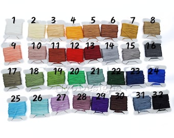 May include: Thirty-two spools of thread in various colors, numbered 1 through 32. The spools are arranged in four rows of eight spools each.