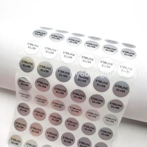 May include: Sheet of round stickers with the words "STERLING SILVER" printed in black on a variety of gray and silver backgrounds. The stickers are arranged in rows and columns on a clear, transparent sheet.