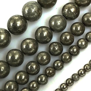 May include: A strand of round, metallic pyrite beads in various sizes. The beads are a dark gray color with a slightly iridescent sheen.