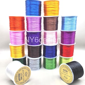 May include: A collection of colorful elastic string spools in various colors, including blue, orange, yellow, and purple. The spools are labeled with Japanese text and are ideal for jewelry making and crafts.