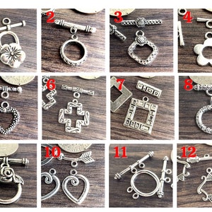 May include: Twelve silver-toned metal toggle clasps with various decorative designs, including hearts, flowers, crosses, and geometric shapes. These clasps are perfect for jewelry making, crafting, and DIY projects.