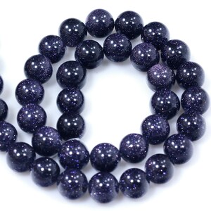 May include: A strand of dark blue gemstone beads with a speckled, glittery finish. The beads are round and uniform in size.