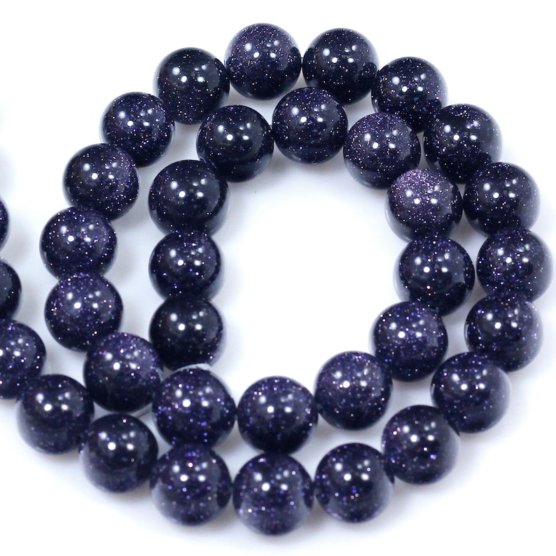 May include: A strand of dark blue gemstone beads with a speckled, glittery finish. The beads are round and uniform in size.