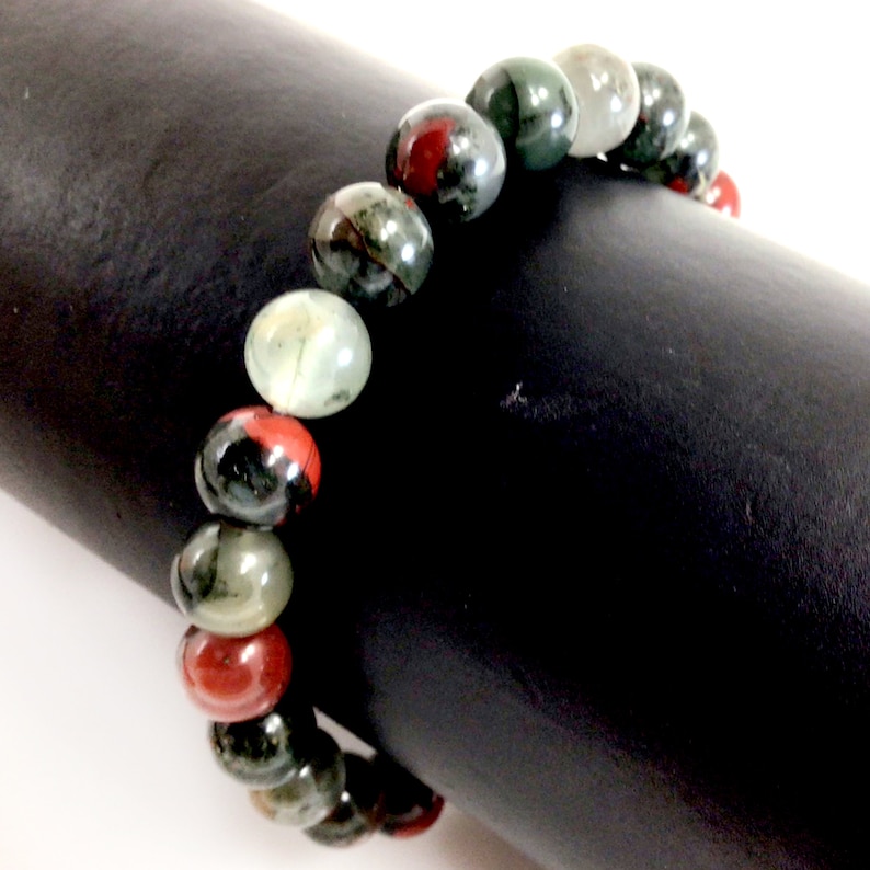 May include: A bracelet made of green, red, and black gemstone beads.