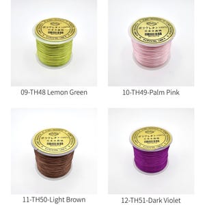 May include: Four spools of thread in various colors: lemon green, palm pink, light brown, and dark violet. Each spool has a gold-colored label with Japanese text and the brand name "CRYSTAL LINE". The thread is tightly wound on a white spool.