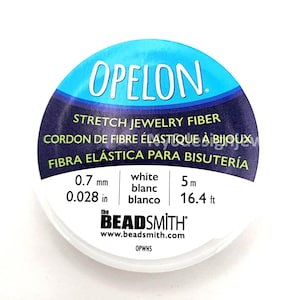 May include: A spool of white OPELON stretch jewelry fiber. The label indicates the fiber is 0.7 mm (0.028 in) thick and 16.4 ft long. The packaging includes the text "the BEADSMITH" and "STRETCH JEWELRY FIBER".