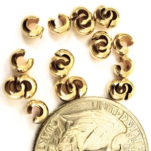 May include: A close-up of 12 gold-toned metal bead caps. The bead caps are about the size of a US quarter. The bead caps are designed to be used as end caps for necklaces, bracelets, or other jewelry.
